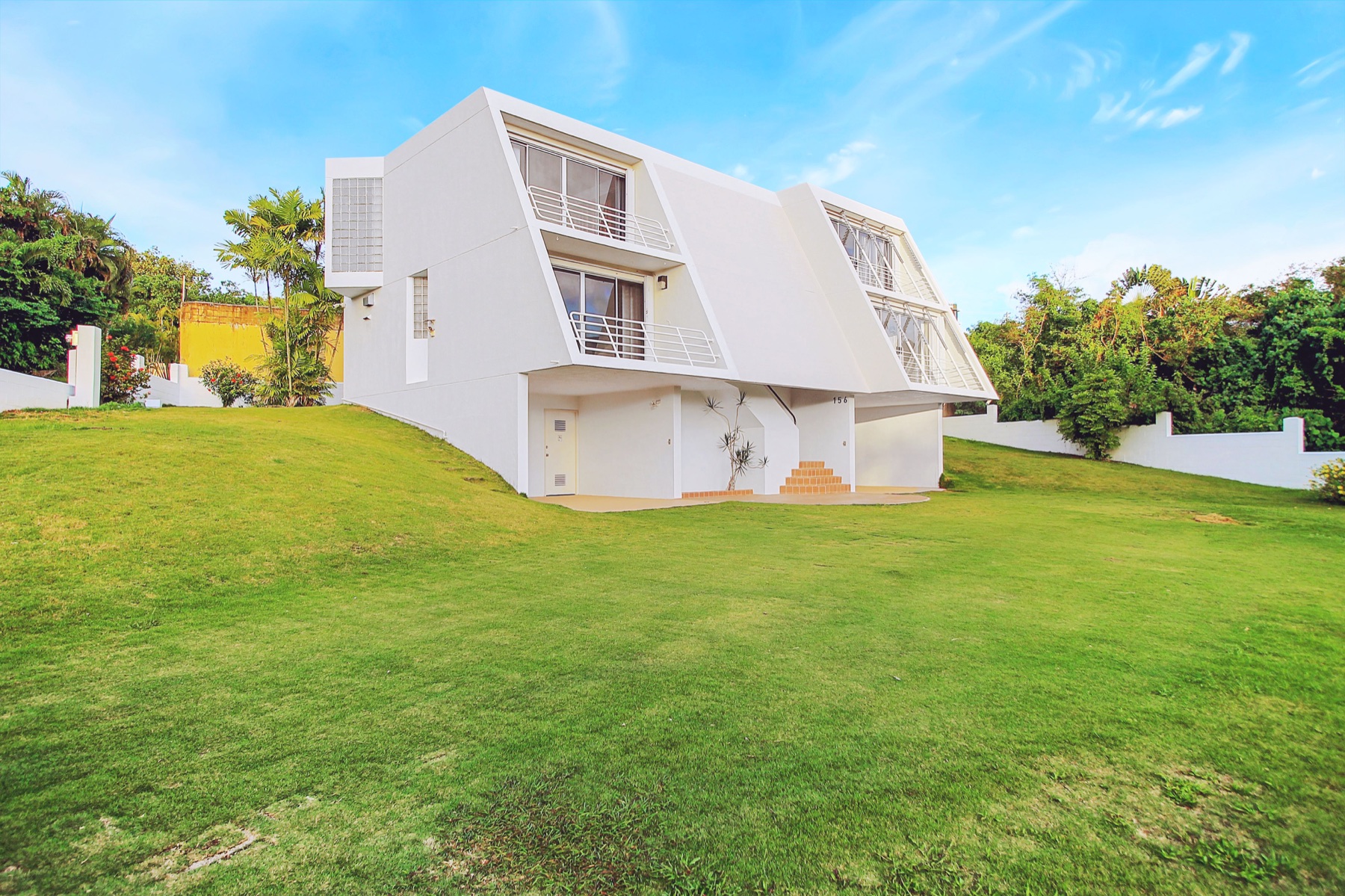 Contemporary white home in Guam with a green lawn